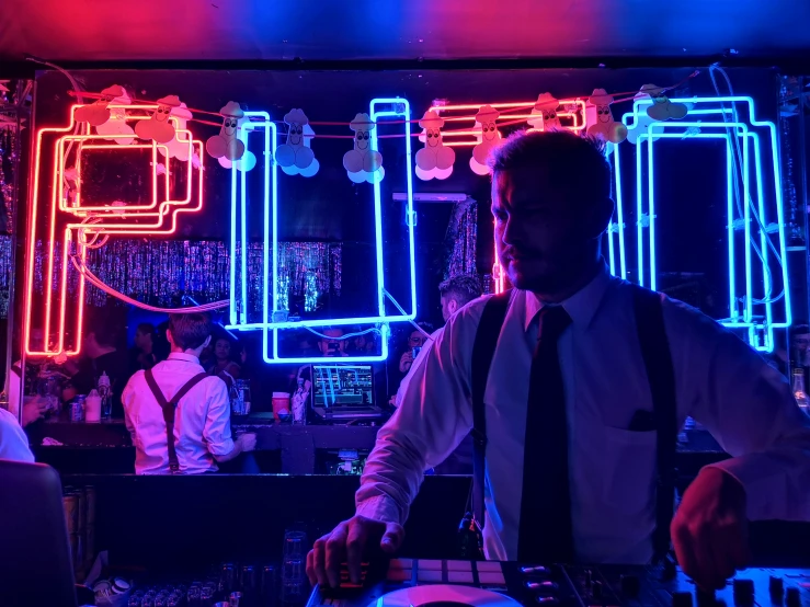man standing in front of neon sign mixing sound equipment