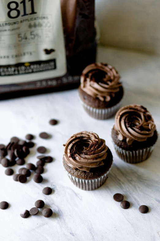 chocolate cupcakes with chocolate chips next to a bag of coffee