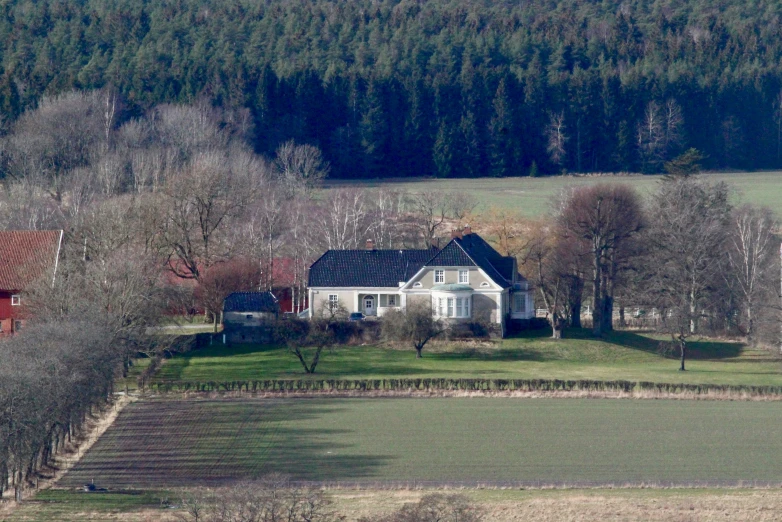 the old farmhouse is seen from above, in a field with trees