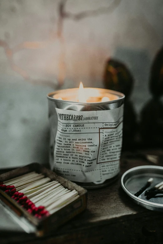 an open tin of cigarettes with one burning and the others on a wooden surface