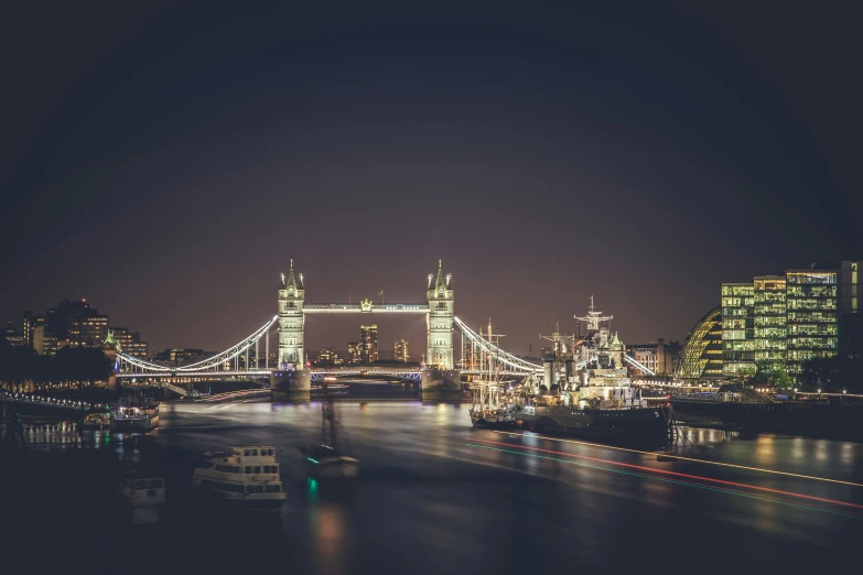 a city is lit up at night and has the london bridge visible