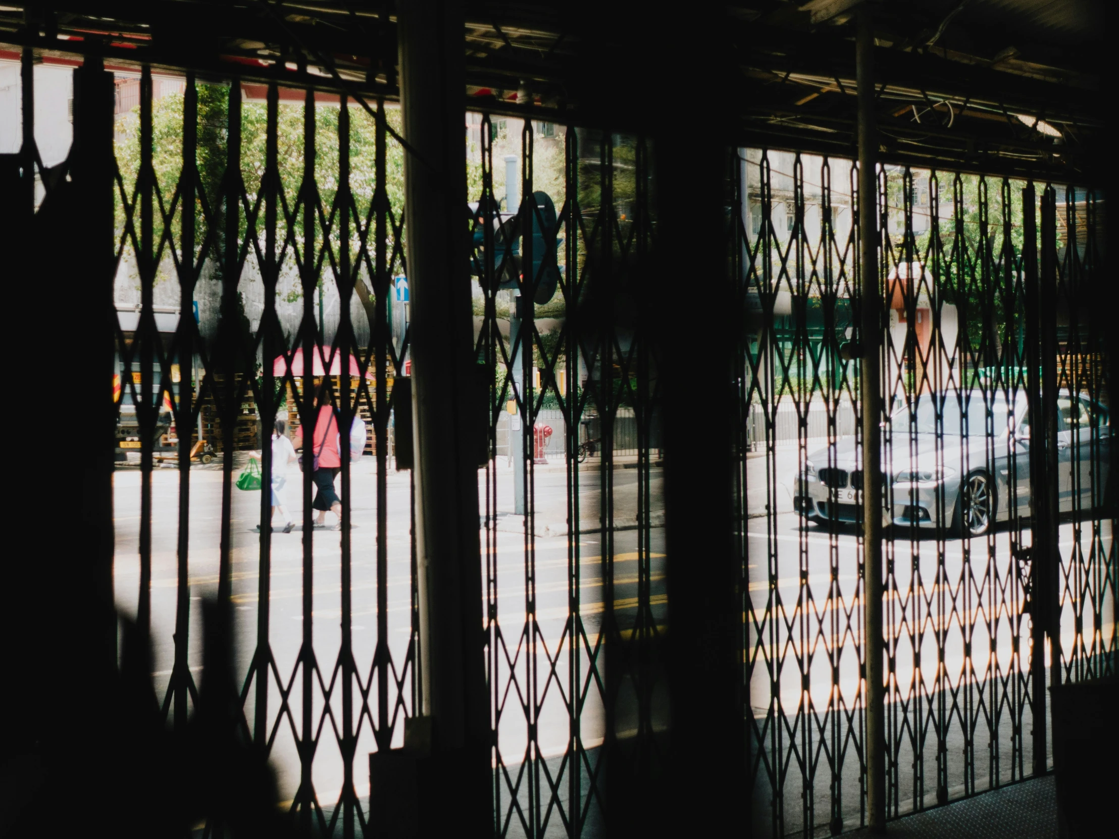 a picture of some people on the street behind some bars