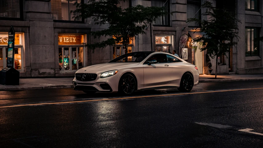 a white car parked on the street in the rain