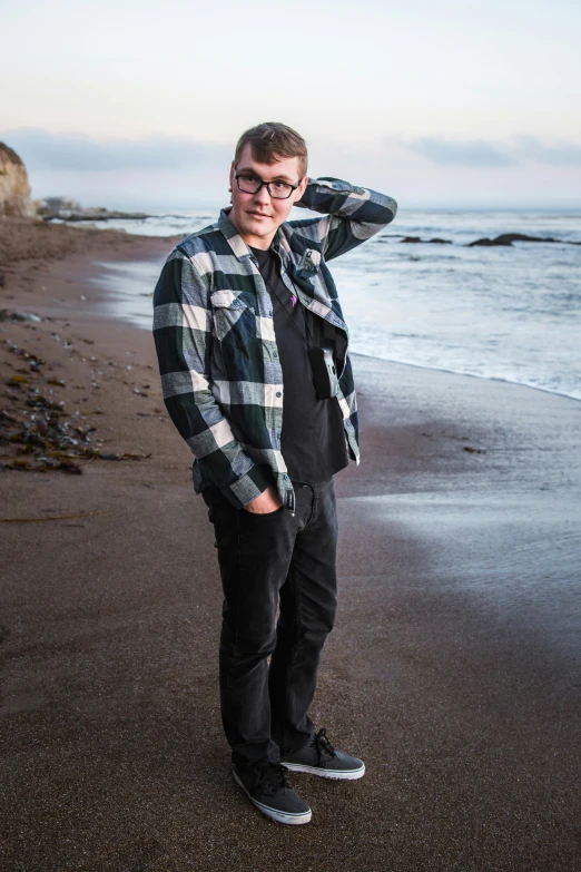 a man is standing on a beach wearing jeans