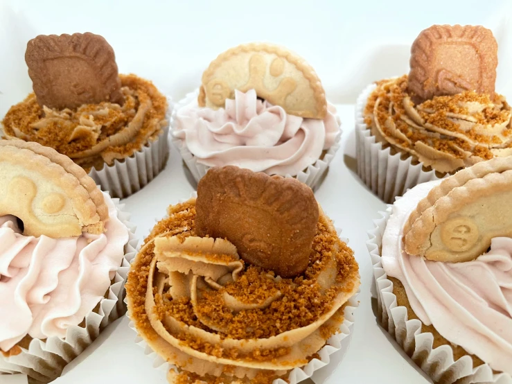 four cupcakes with icing on a white surface