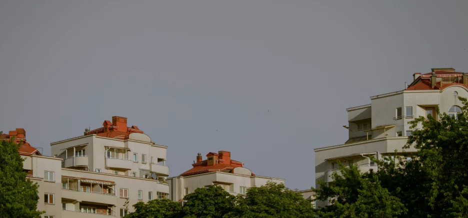 several buildings against the gray sky with trees