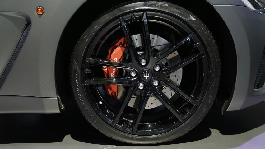 a gray sports car with orange and black wheels