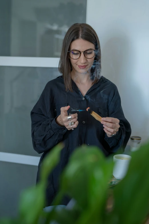 a woman smoking a cigarette and standing near a plant