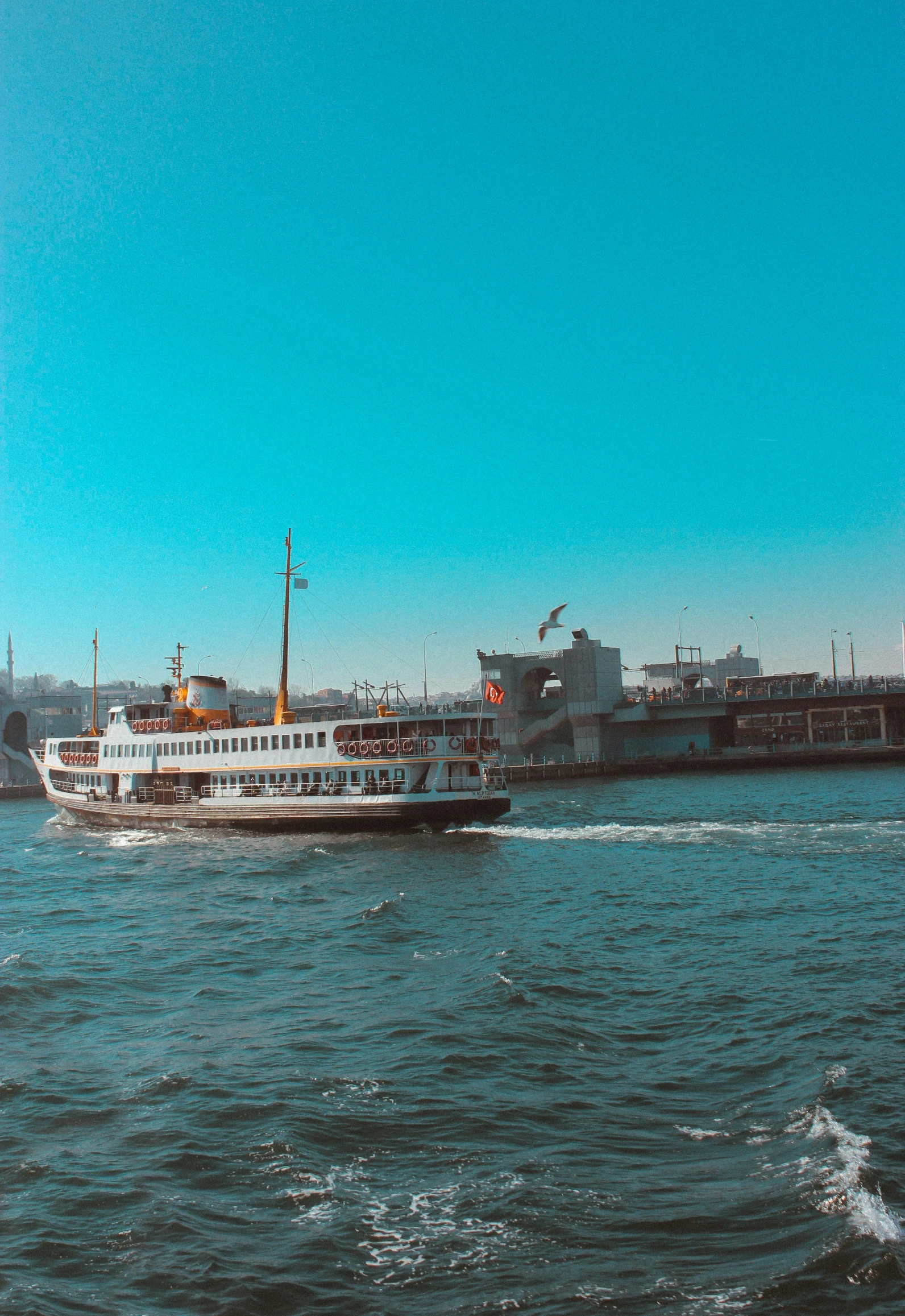 a white ferry traveling through the ocean past an industrial building