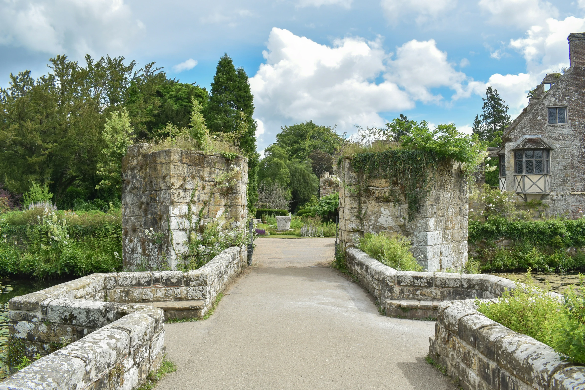 a walkway made up of old stones, leading to some small buildings