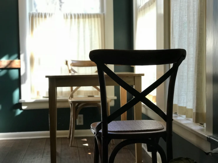 a chair sitting near an open window and table