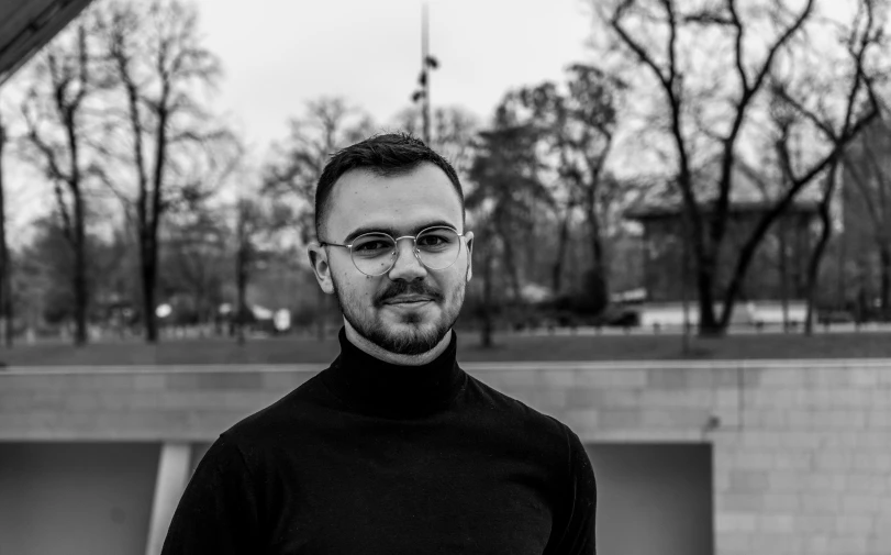 a man standing near a wall in the middle of a park