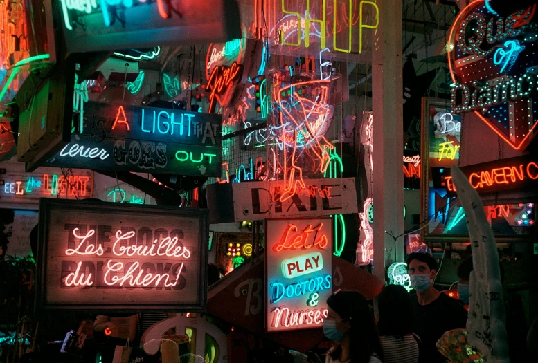 a woman standing near many neon signs that say neon