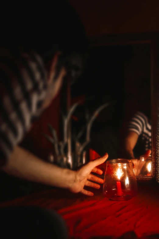 someone holds their hands in front of a group of candles