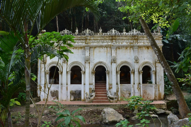 an old house in the jungle with steps leading up to a staircase