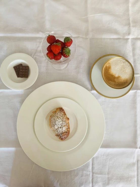 a close up of two plates and a bowl of strawberries on a table