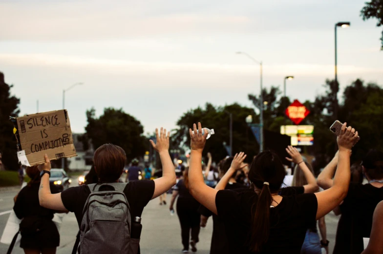 some people protesting on a city street with a sign