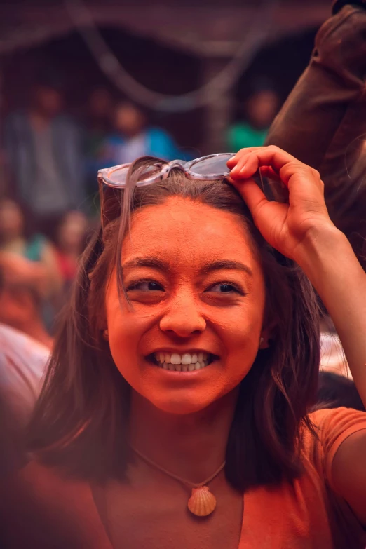young lady smiling in crowd, holding head piece over her hair