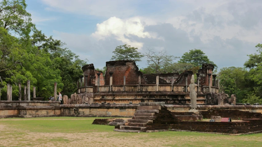 a large stone structure with some trees and people in front of it