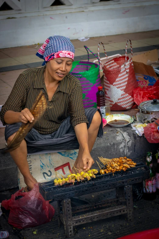 man with head scarf making food on a cart