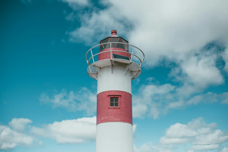 a large red and white lighthouse in the middle of a grassy area