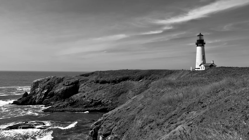 a black and white pograph of a lighthouse on the edge of a cliff