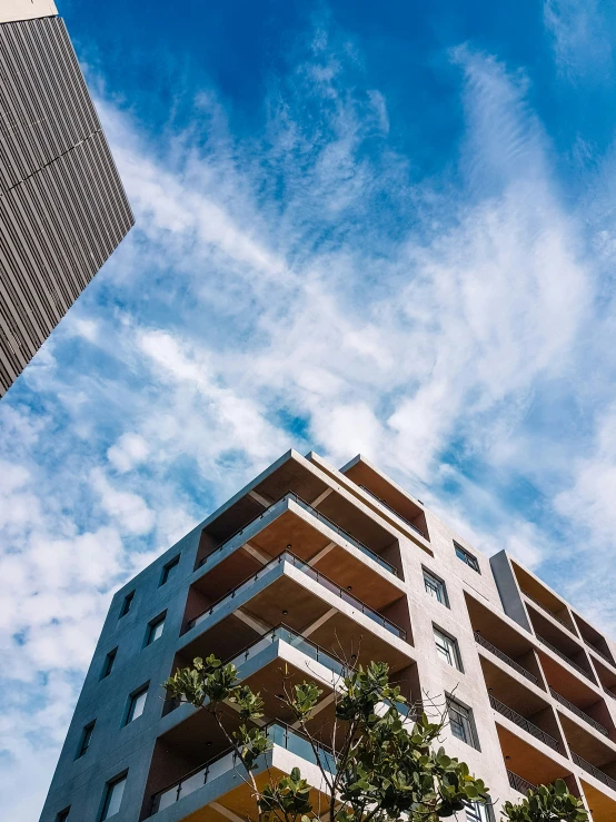 a tall brown building with trees in the foreground