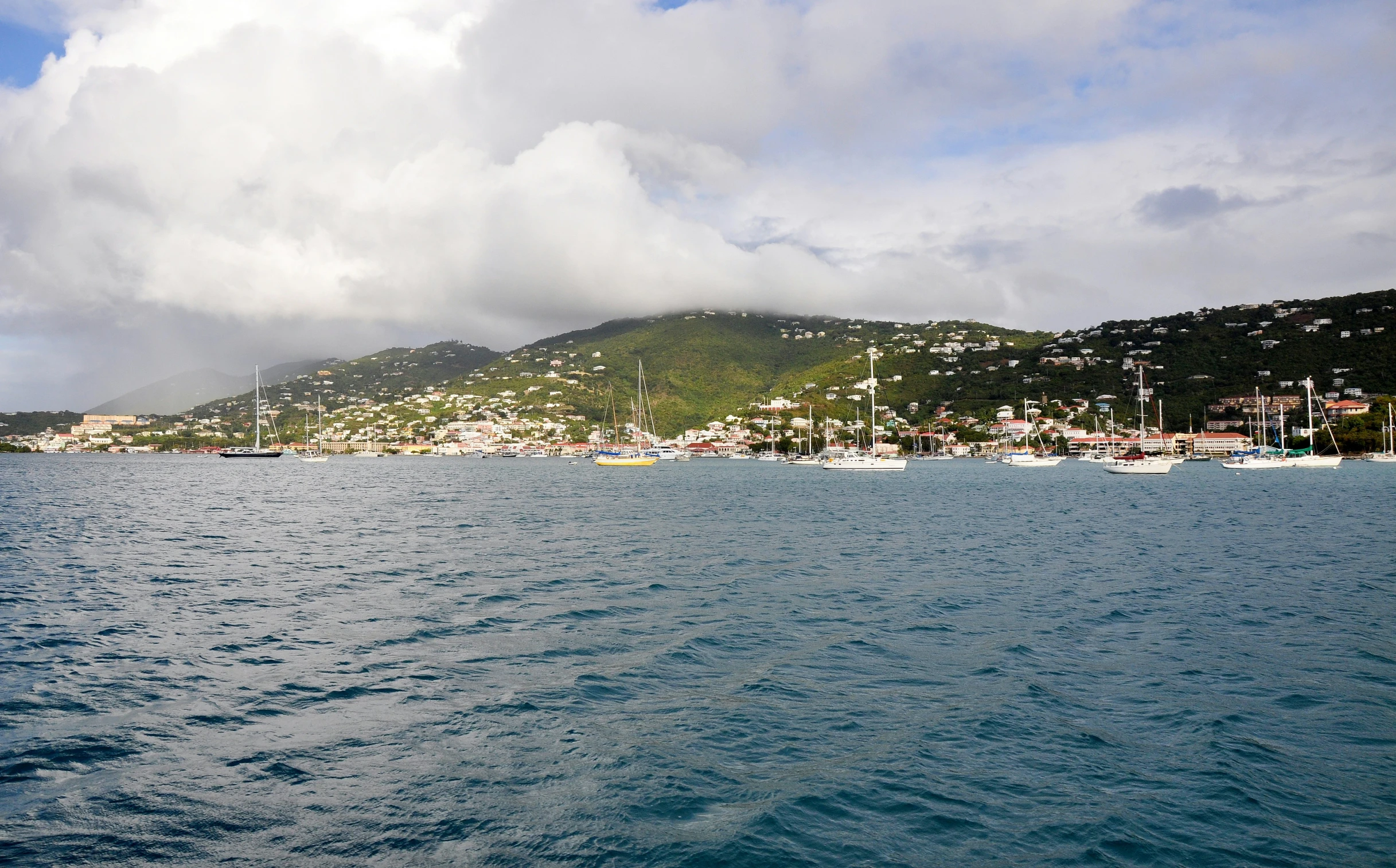 the ocean with a mountain and some boats