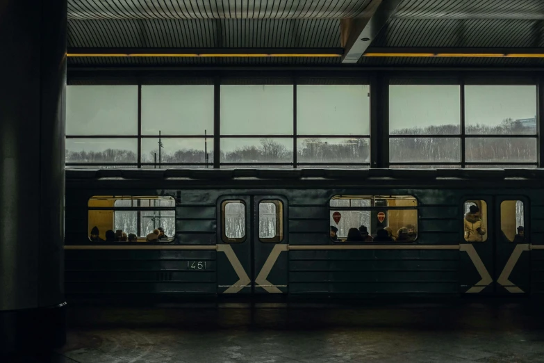 a subway train sitting next to a window with people inside