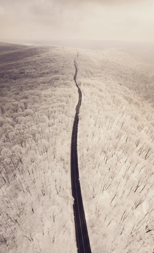 a road winds through the snowy hills on an overcast day