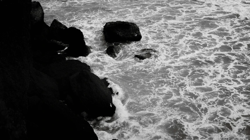 a black and white po of two people sitting on the rocks in the water