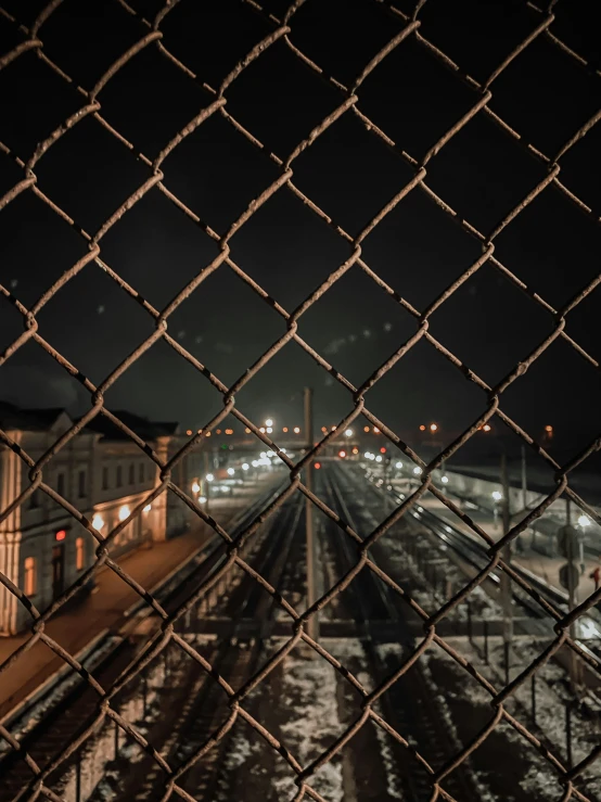 a city street with tracks in the foreground through a chain link fence