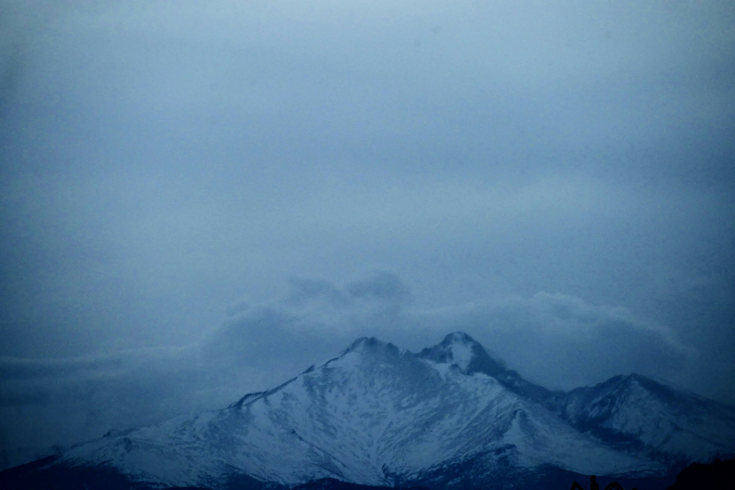 the tops of snow covered mountain ranges in a twilight sky