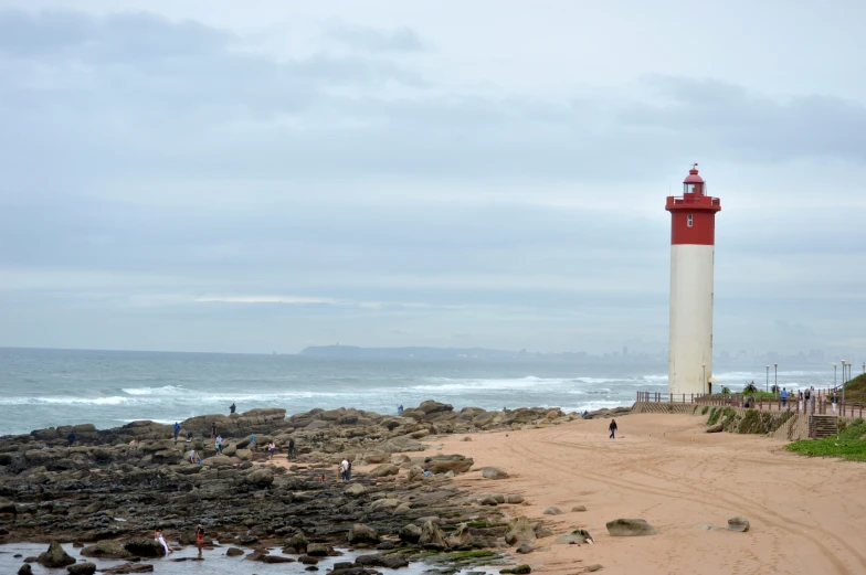 a very tall red and white lighthouse near the ocean