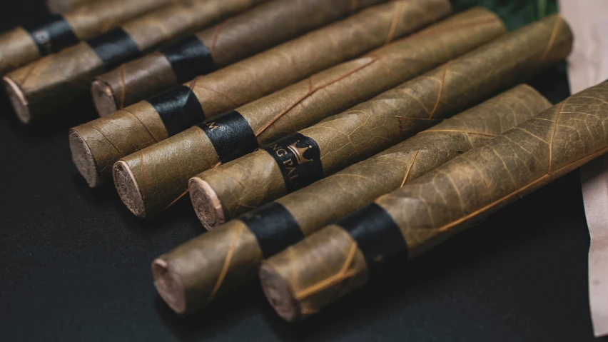 four black and brown cigars next to a few white buds