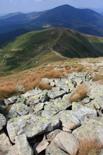 rocky terrain in front of a mountain range with grass and mountains