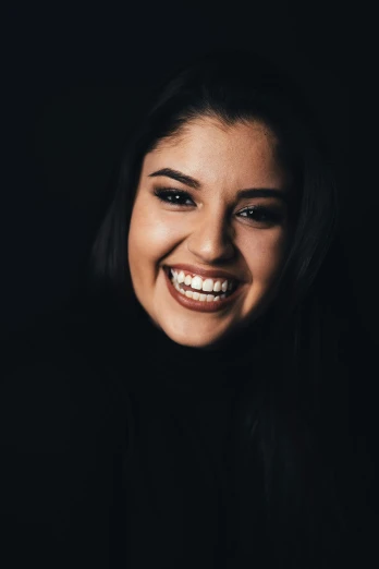 a woman smiling and posing with the dark background