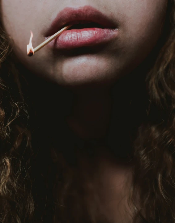 a close up po of a woman with her nose on a match stick