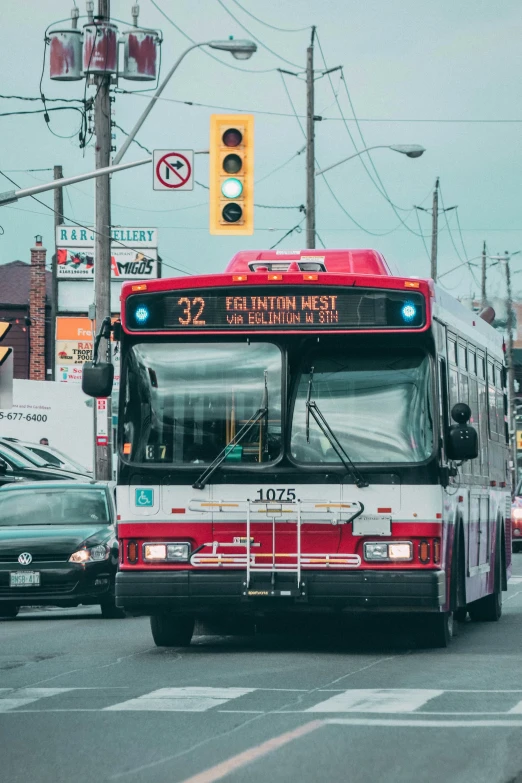 a red and white bus on street next to traffic lights