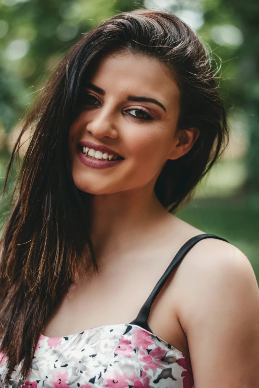 a close up of a woman smiling wearing a floral dress