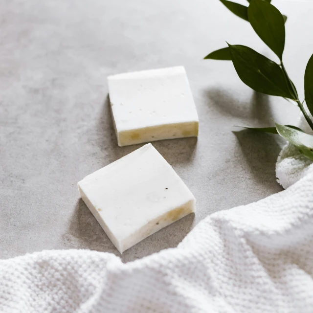 two bars of soap with a white towel next to it