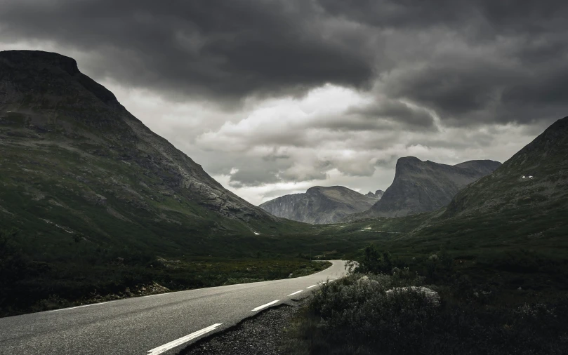 a long empty street is next to some mountains