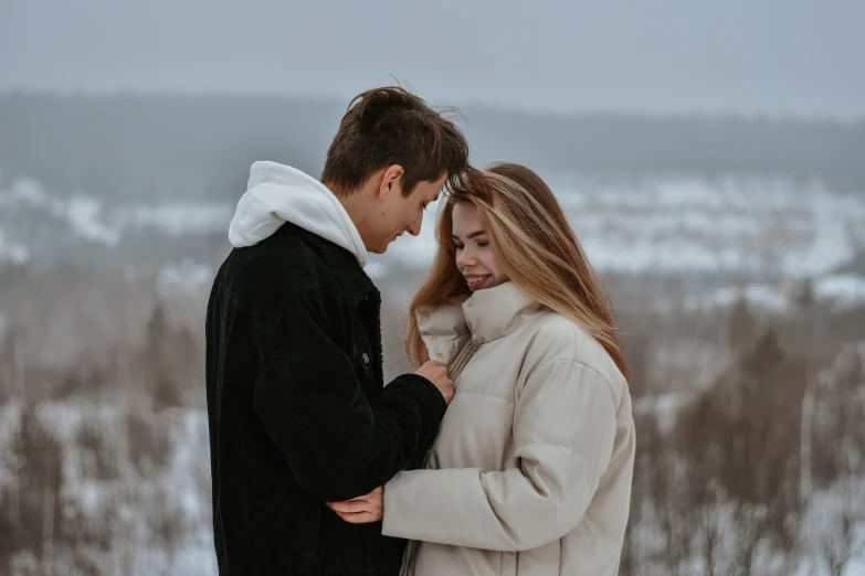 a man and a woman hugging each other on a snow covered hill