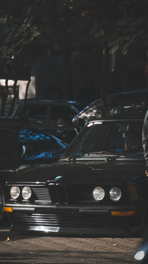 a woman walking next to two cars on a street