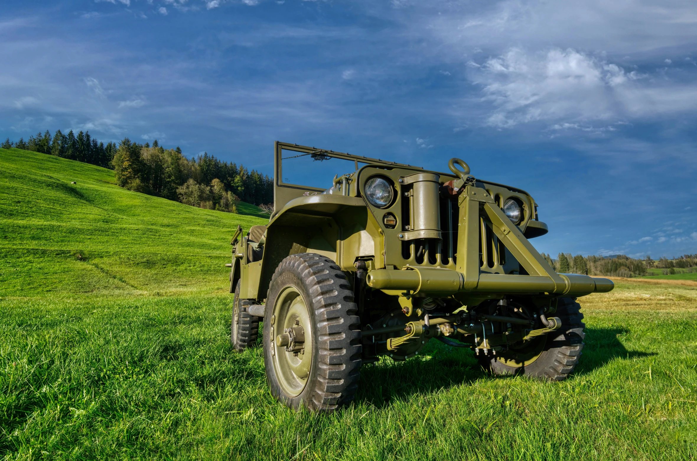 an old truck sitting on a green grassy hill