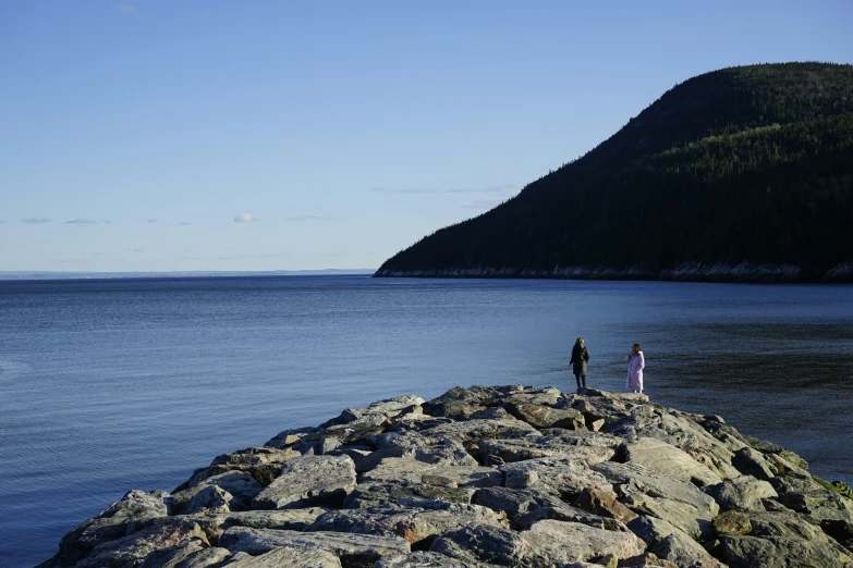 two people standing at the edge of a large body of water