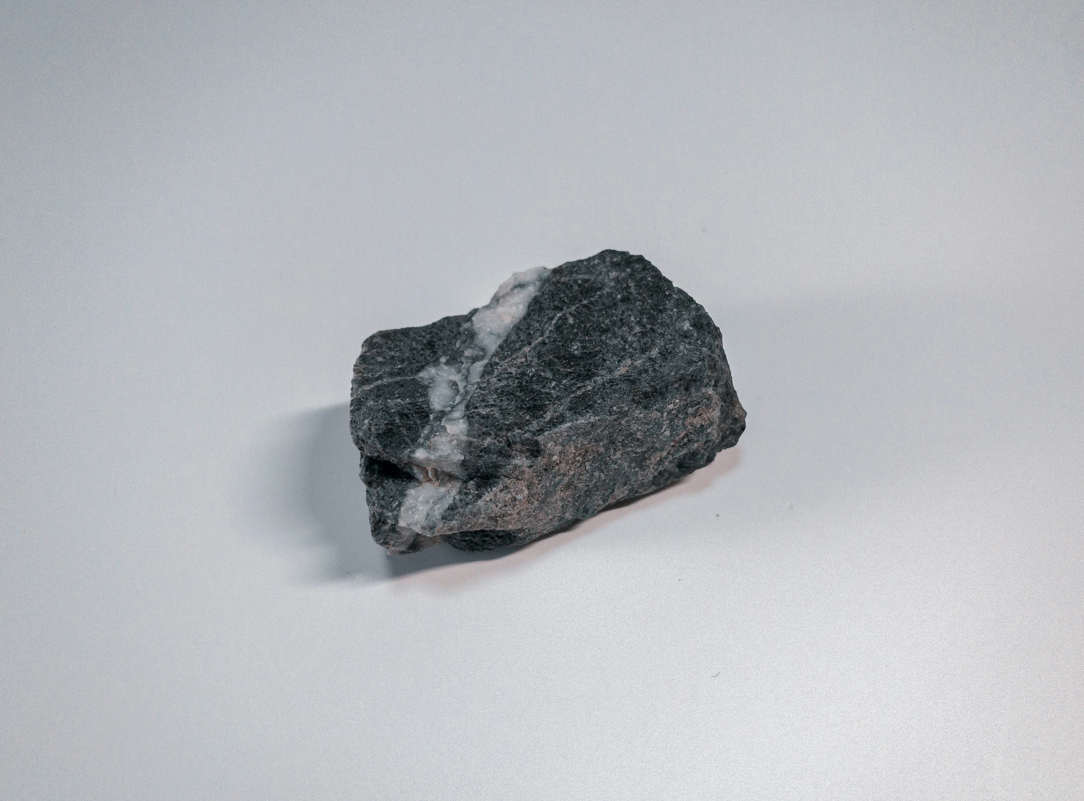 a rock with white and gray snow on the ground