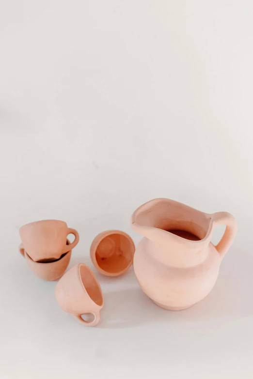 three clay containers and a vase with cups below