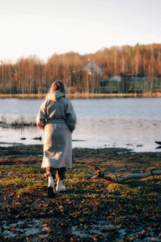 a woman in a white coat walking across a field