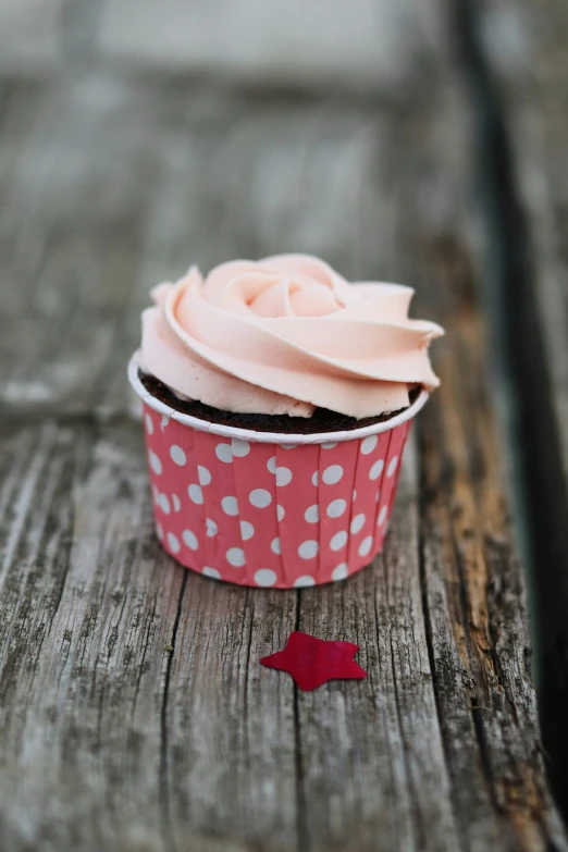 cupcake with pink frosting on a wooden table